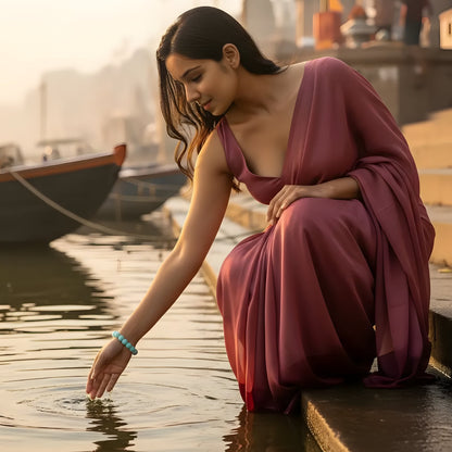 Woman in a red dress sitting by a waterfront with boats in the background